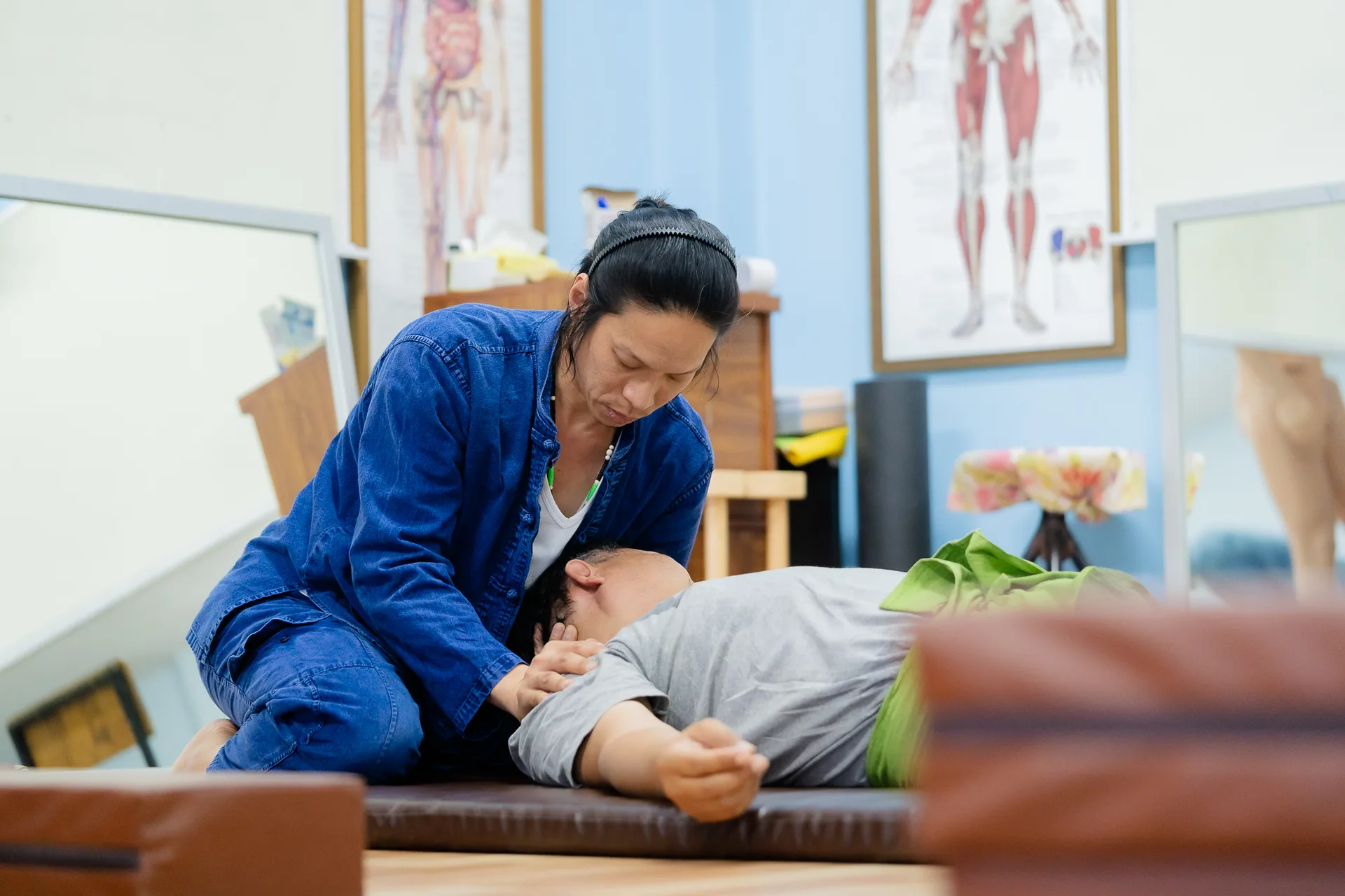 Thara Massage session at the practice, anatomy charts on the wall